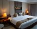Hotel bed with a white fitted mattress protector visible under the sheet